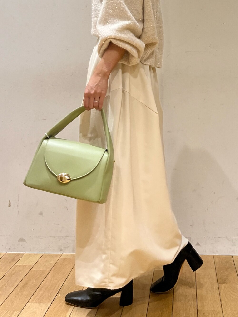 ホワイト系のスカート、ホワイト系のカーディガン/ボレロ、グリーン系のハンドバッグを着用したレディースの秋コーディネートの6枚目の写真