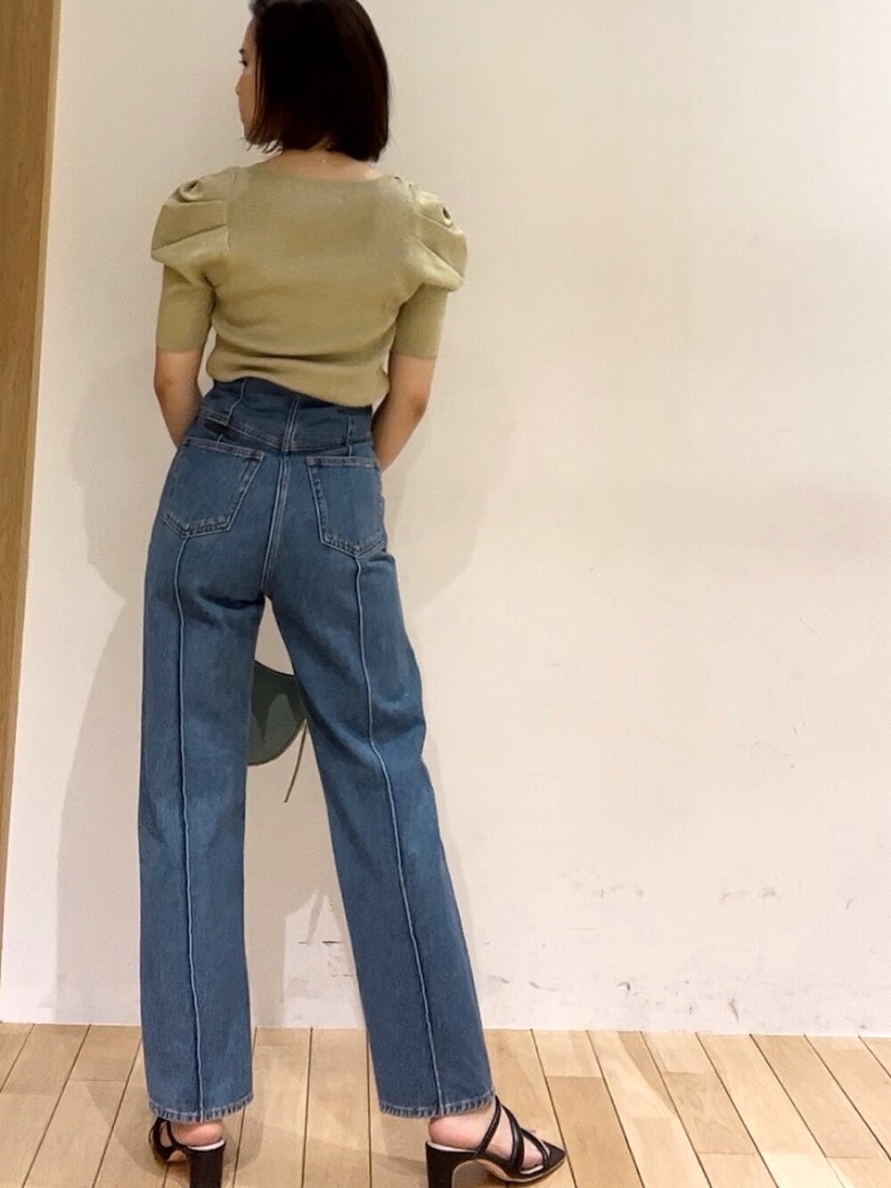 ベージュ系のニット/セーター、ブルー系のデニムパンツ、グリーン系のハンドバッグを着用したレディースの春コーディネートの3枚目の写真