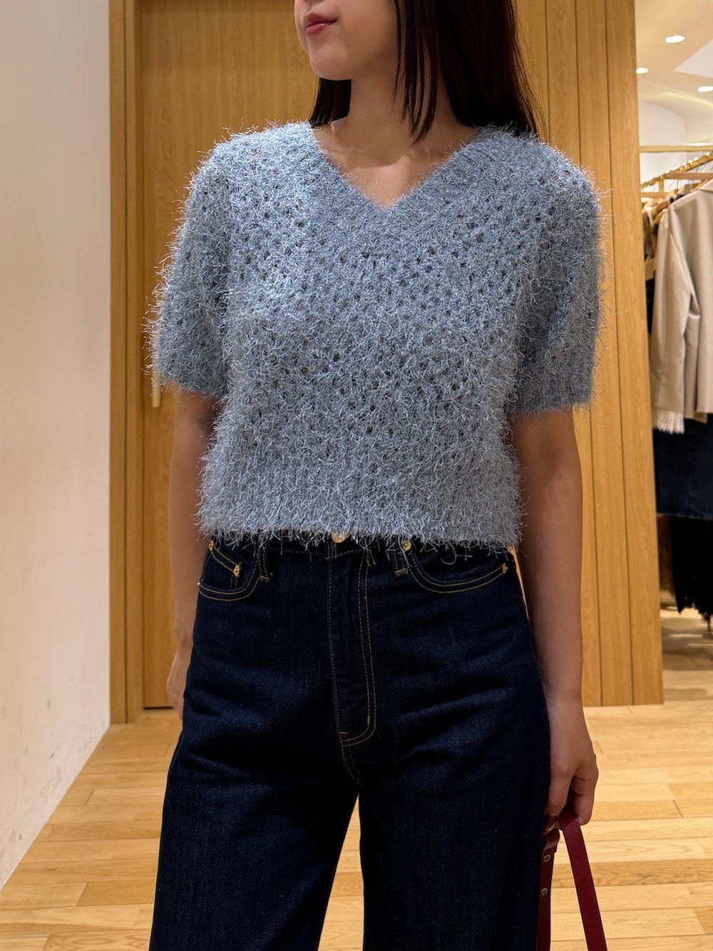 ブルー系のデニムパンツ、レッド系のハンドバッグ、ブルー系のニット/セーターを着用したレディースの秋コーディネートの4枚目の写真