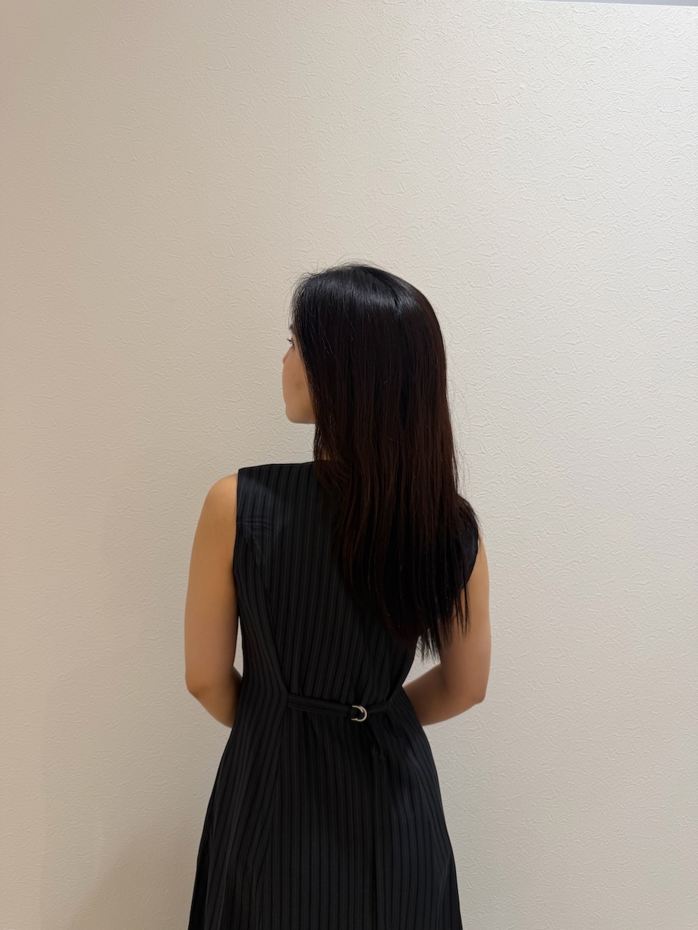 ブラック系のワンピース、ブラック系のハンドバッグ、シルバー系のパンプスを着用したレディースの夏コーディネートの6枚目の写真