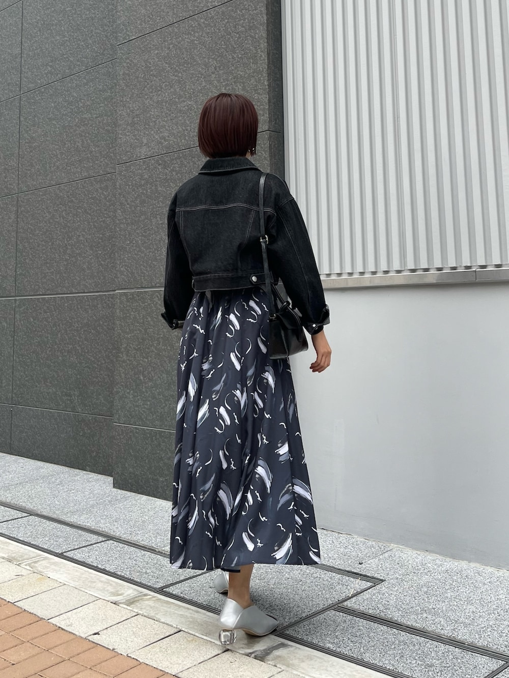 ブラック系のハンドバッグ、ブルー系のワンピース、シルバー系のパンプスを着用したレディースの春コーディネートの3枚目の写真