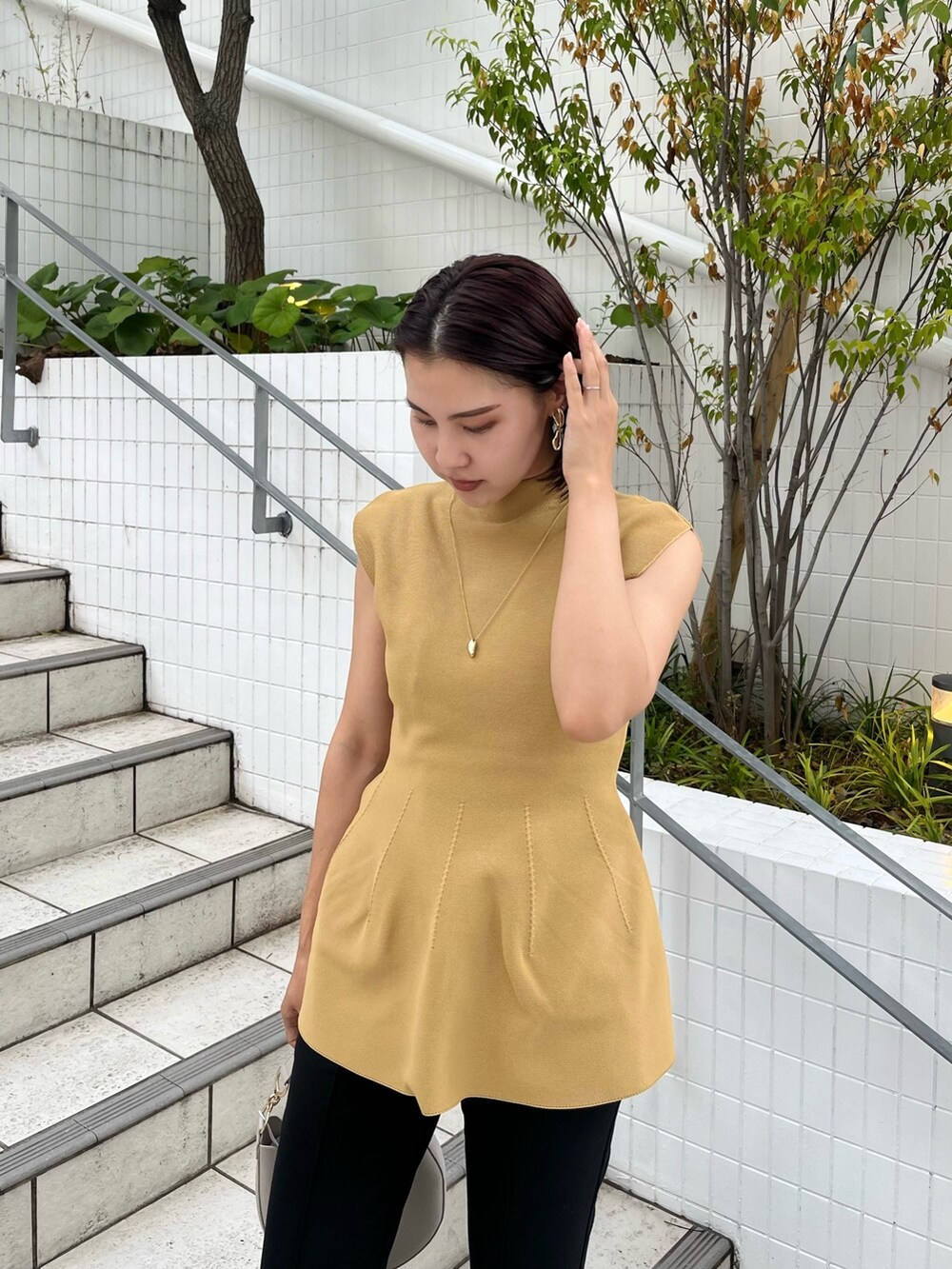 イエロー系のニット/セーター、ホワイト系のハンドバッグ、ブラック系のその他パンツを着用したレディースの秋コーディネートの2枚目の写真