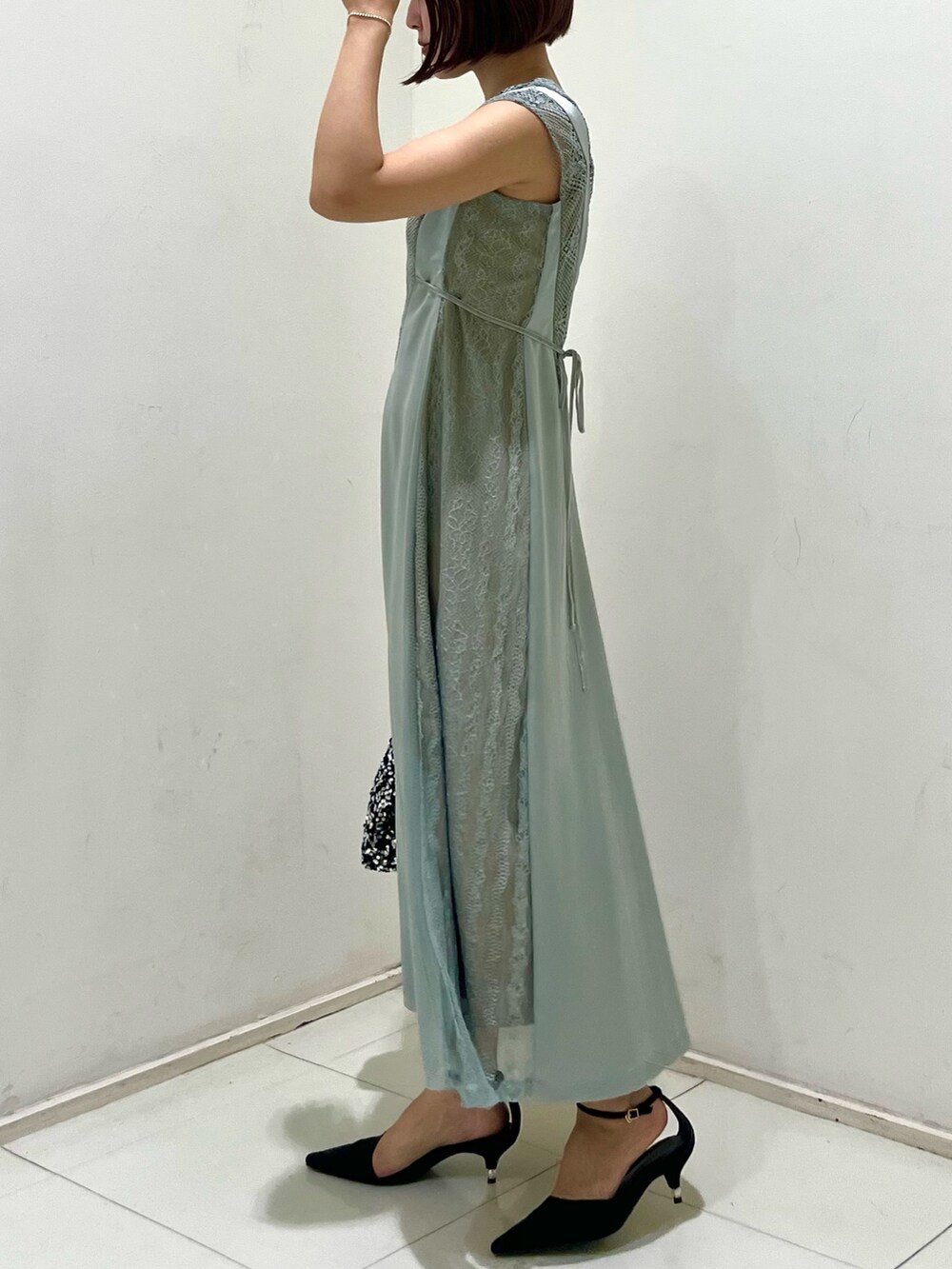 シルバー系のハンドバッグ、ブラック系のパンプス、グリーン系のドレスを着用したレディースの秋コーディネートの2枚目の写真