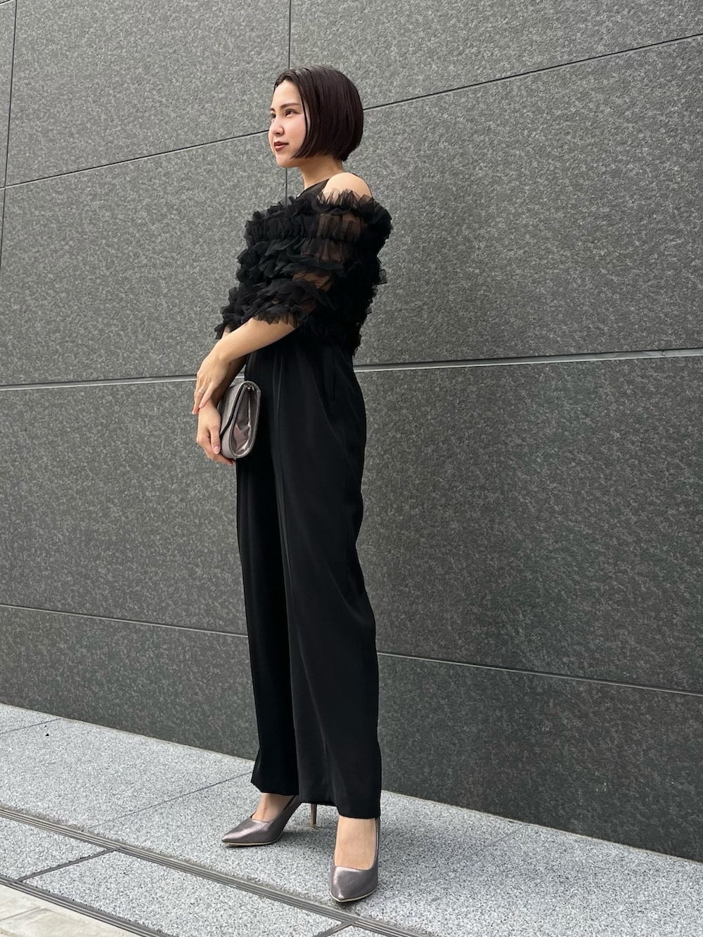 グリーン系のトレンチコート、シルバー系のパンプス、ブラック系のパンツドレスを着用したレディースの春コーディネートの8枚目の写真