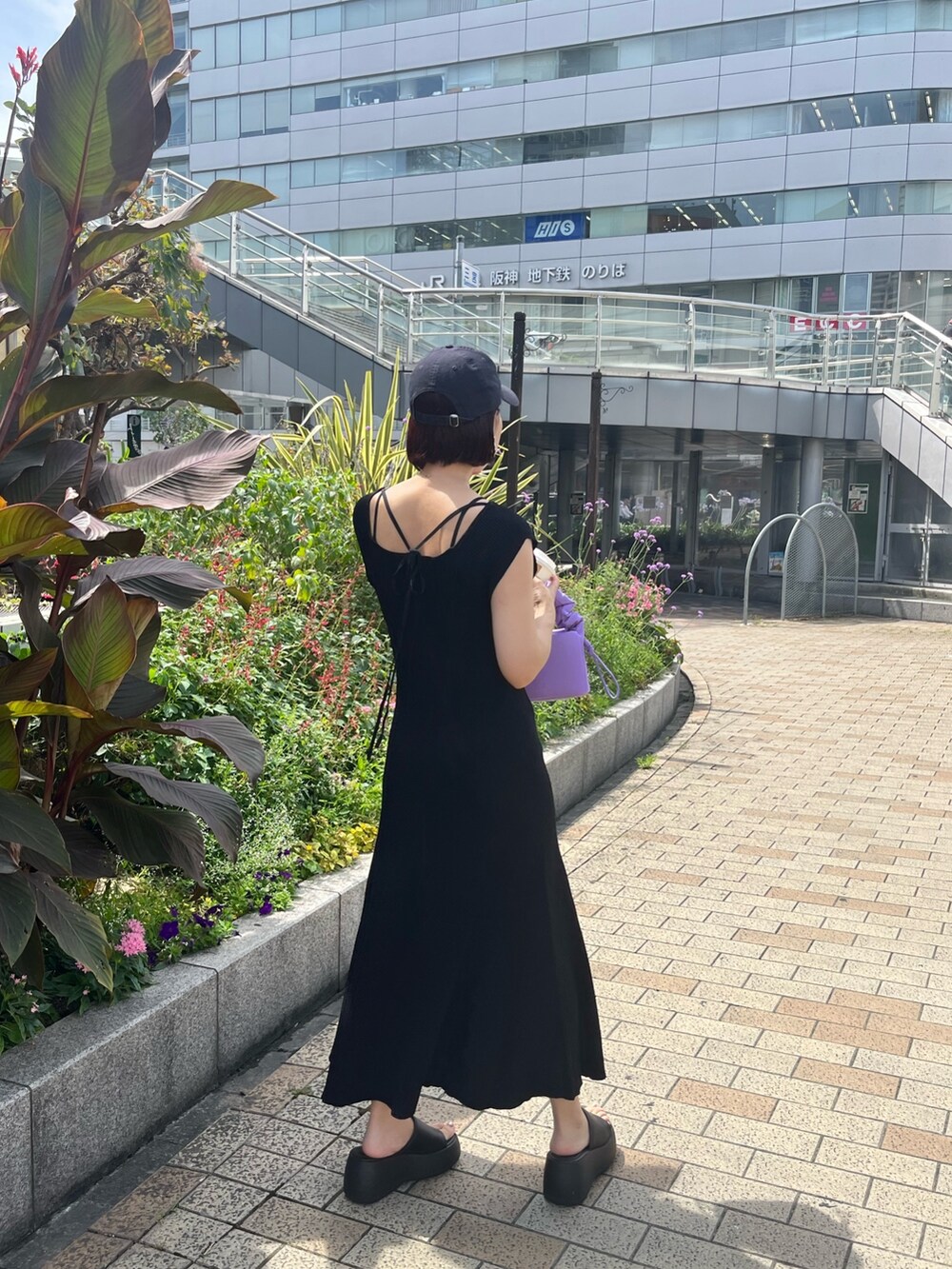 パープル系のハンドバッグ、ブラック系のワンピースを着用したレディースの夏コーディネートの3枚目の写真