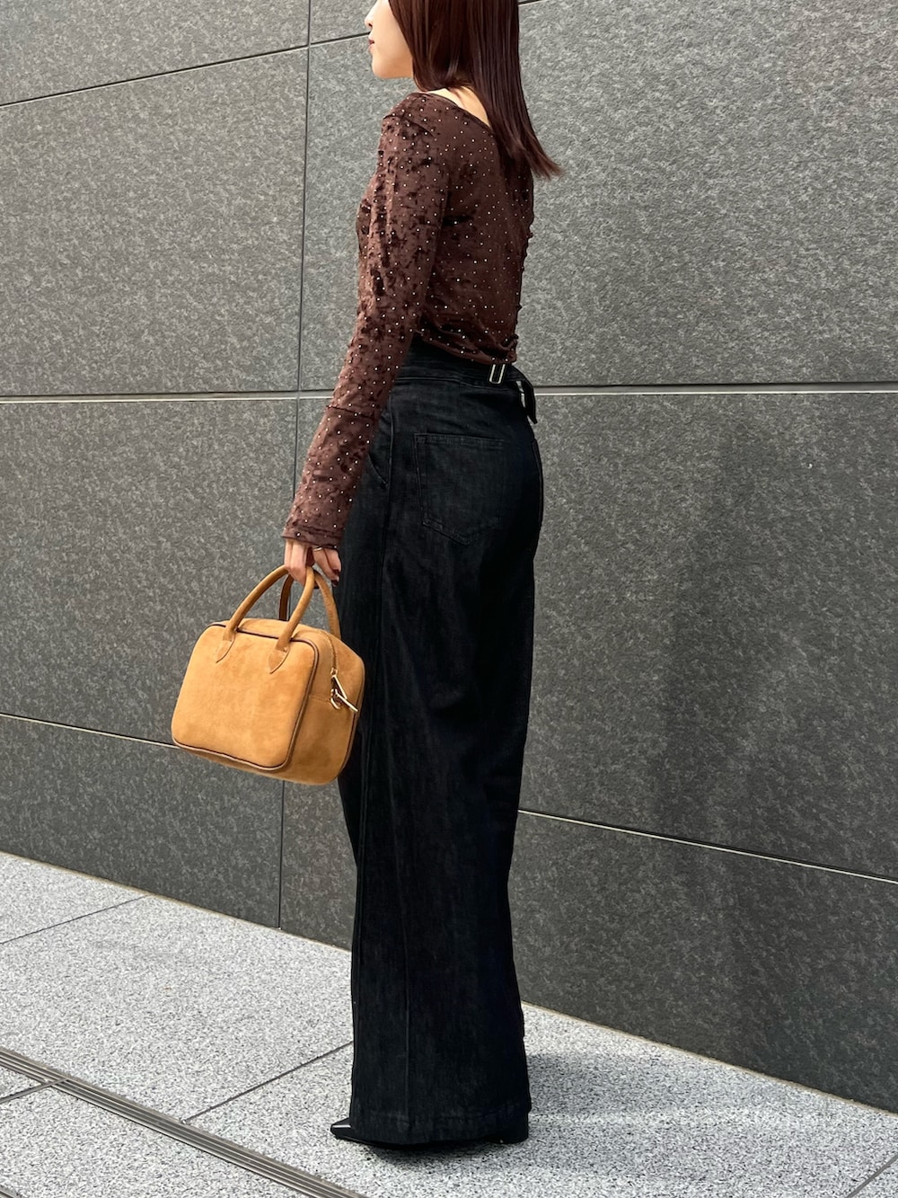 ブラック系のデニムパンツ、ブラウン系のハンドバッグ、ブラウン系のTシャツ/カットソーを着用したレディースの秋コーディネートの3枚目の写真