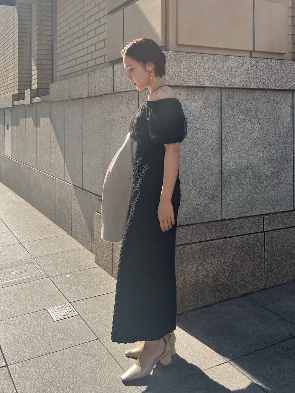 ブラック系のドレス、ベージュ系のパンプスを着用したレディースの冬コーディネートの2枚目の写真