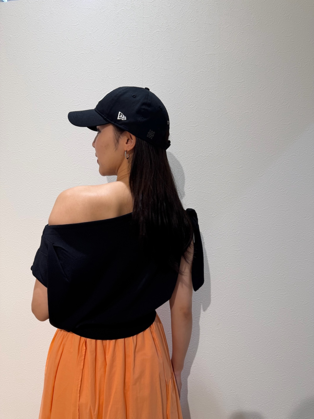 ブラック系のパンプス、ブラウン系のハンドバッグ、オレンジ系のスカートを着用したレディースの夏コーディネートの6枚目の写真