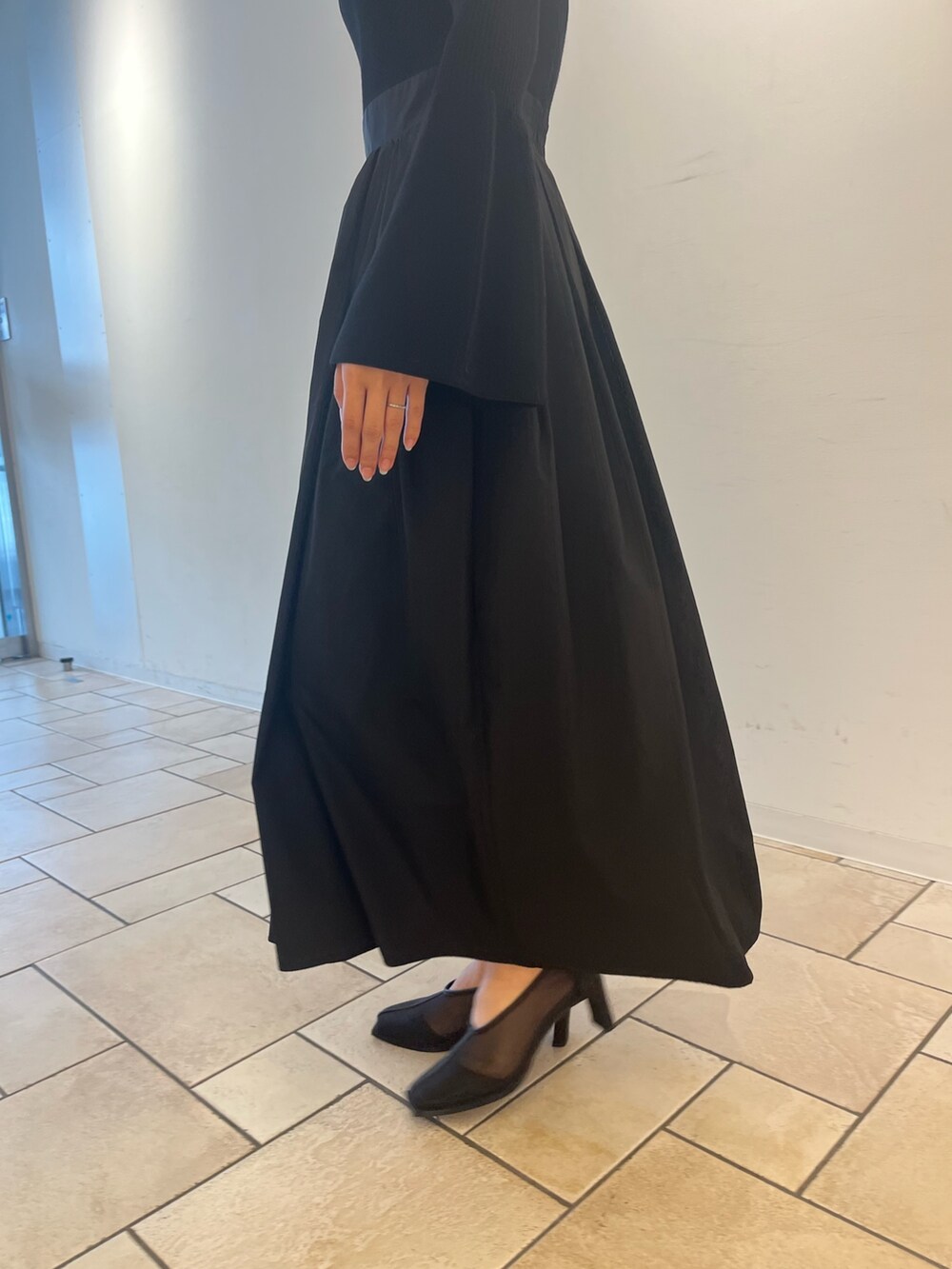 ブラック系のワンピース、ホワイト系のハンドバッグ、ブラック系のパンプスを着用したレディースの秋コーディネートの6枚目の写真