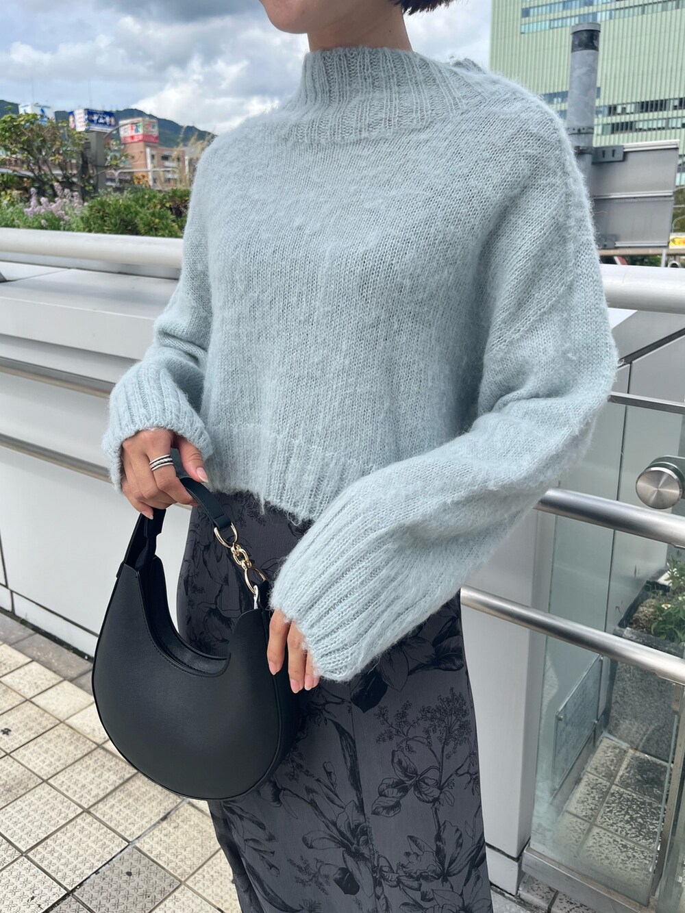 グリーン系のニット/セーター、ブラック系のハンドバッグ、グレー系のスカートを着用したレディースの秋コーディネートの4枚目の写真