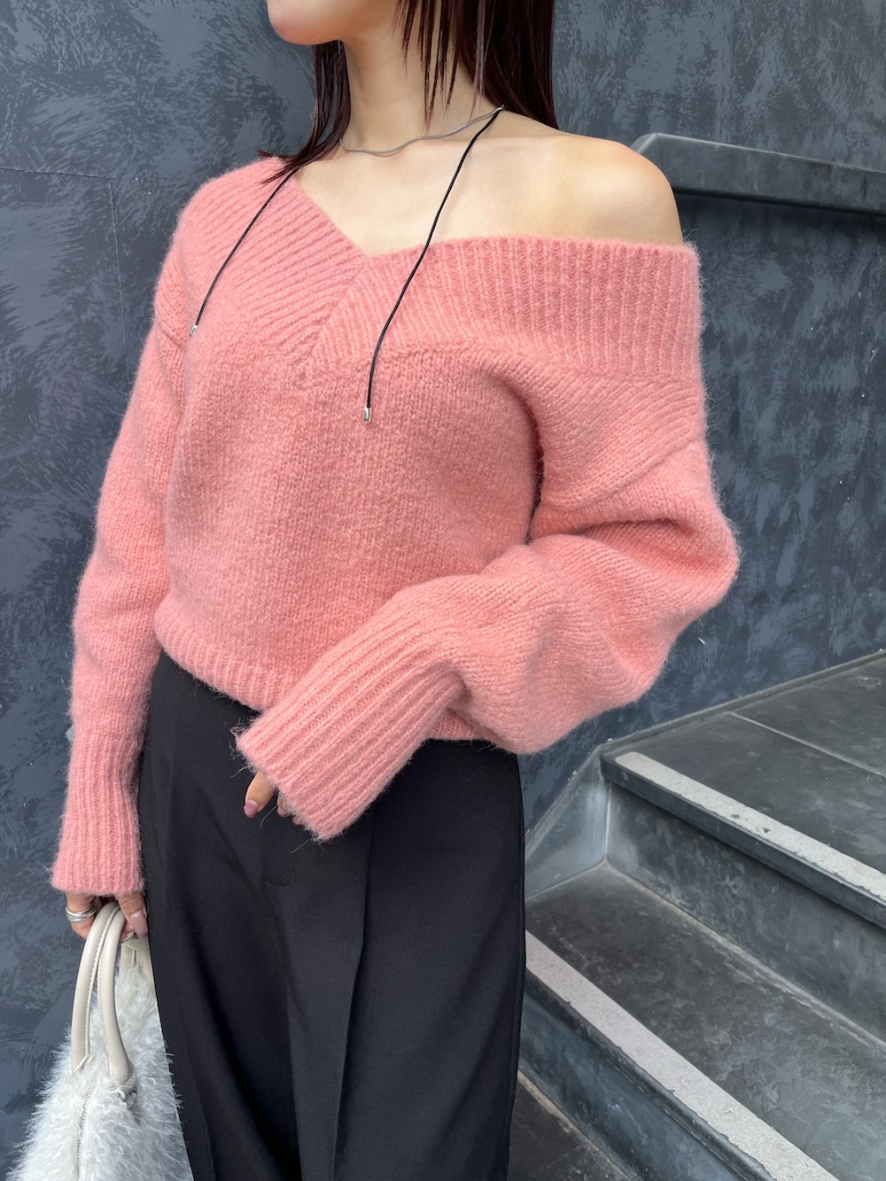 ブラック系のブーツ、ピンク系のニット/セーター、ホワイト系のボストンバッグを着用したレディースの秋コーディネートの4枚目の写真