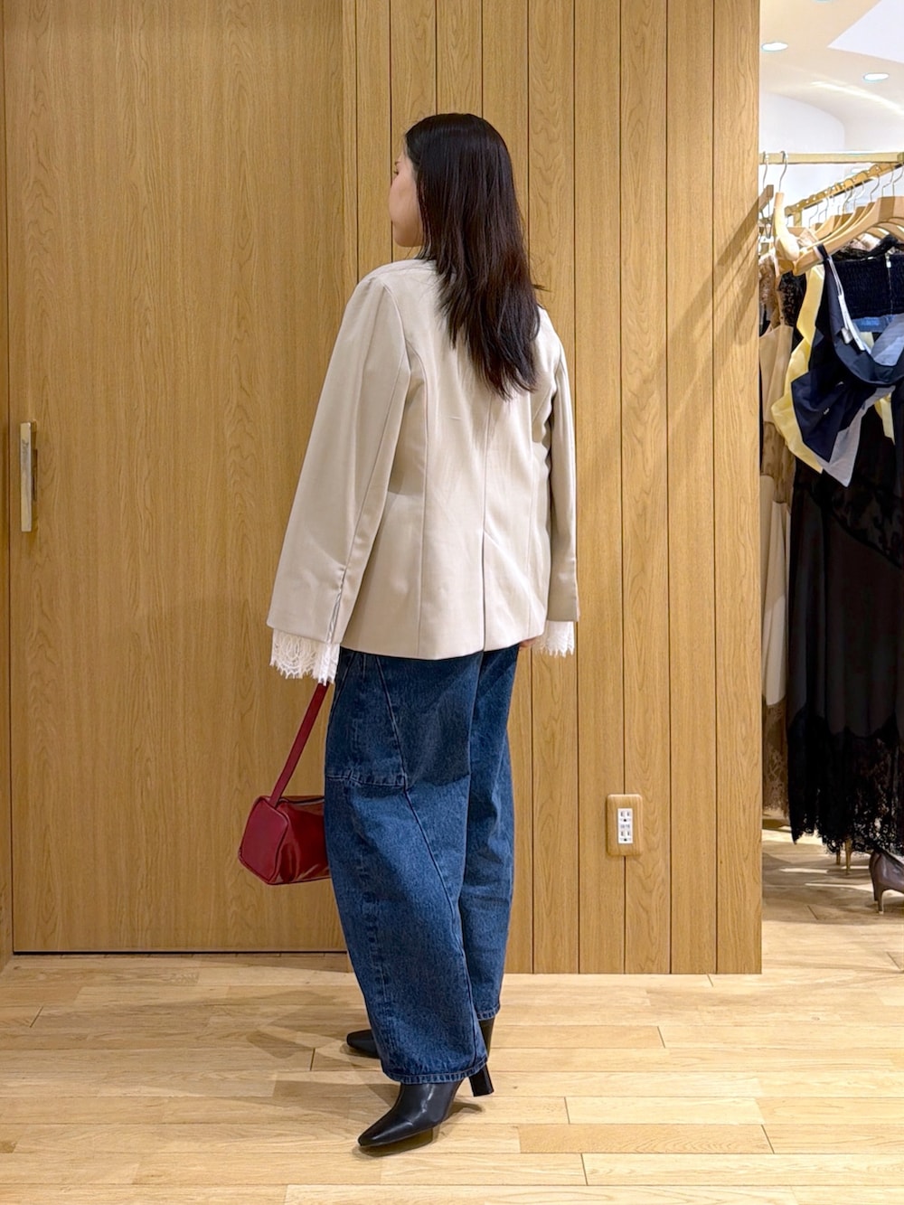 ブルー系のデニムパンツ、レッド系のハンドバッグ、ブラック系のブーツを着用したレディースの秋コーディネートの2枚目の写真