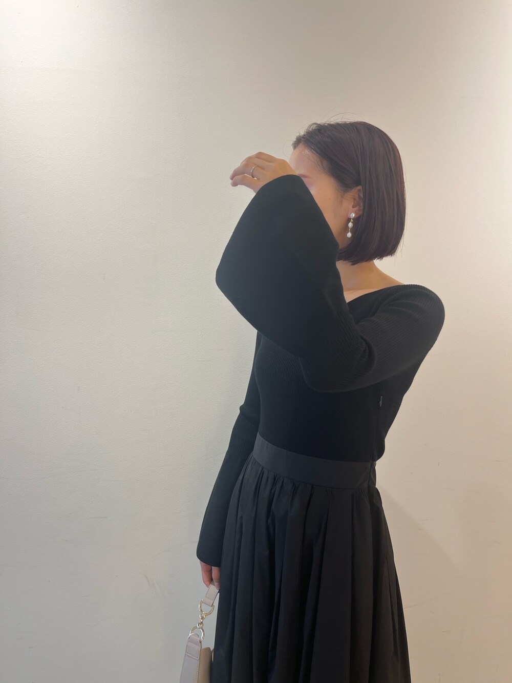 ブラック系のワンピース、ホワイト系のハンドバッグ、ブラック系のパンプスを着用したレディースの秋コーディネートの4枚目の写真