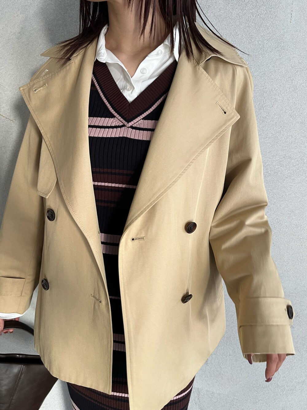 ブラウン系のハンドバッグ、ブラウン系のワンピース、ベージュ系のトレンチコートを着用したレディースの冬コーディネートの7枚目の写真