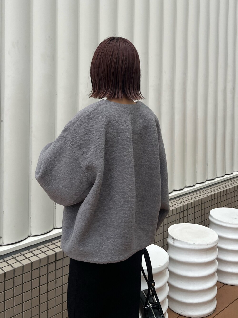 グレー系のブルゾン、ホワイト系のTシャツ/カットソー、ブラック系のショルダーバッグを着用したレディースの秋コーディネートの6枚目の写真