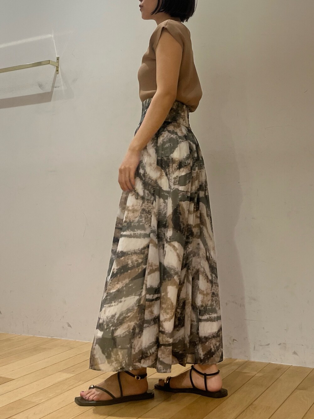 グレー系のスカート、ブラウン系のニット/セーター、ブラック系のサンダルを着用したレディースの夏コーディネートの3枚目の写真