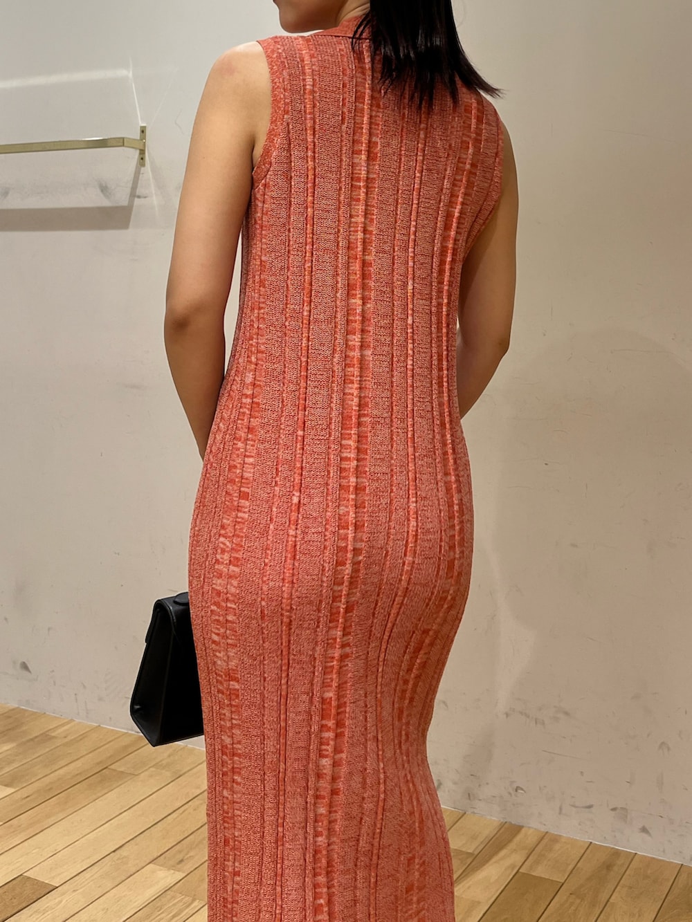 ブラック系のハンドバッグ、ブラック系のサンダル、オレンジ系のワンピースを着用したレディースの夏コーディネートの5枚目の写真