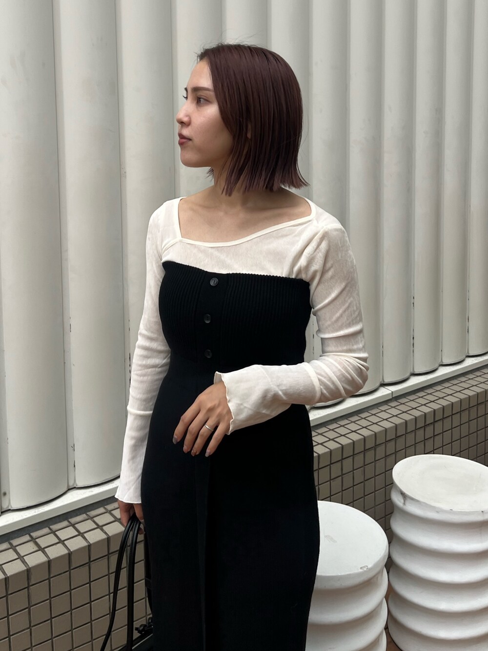 ブラック系のショルダーバッグ、ブラック系のワンピース、ホワイト系のTシャツ/カットソーを着用したレディースの秋コーディネートの5枚目の写真