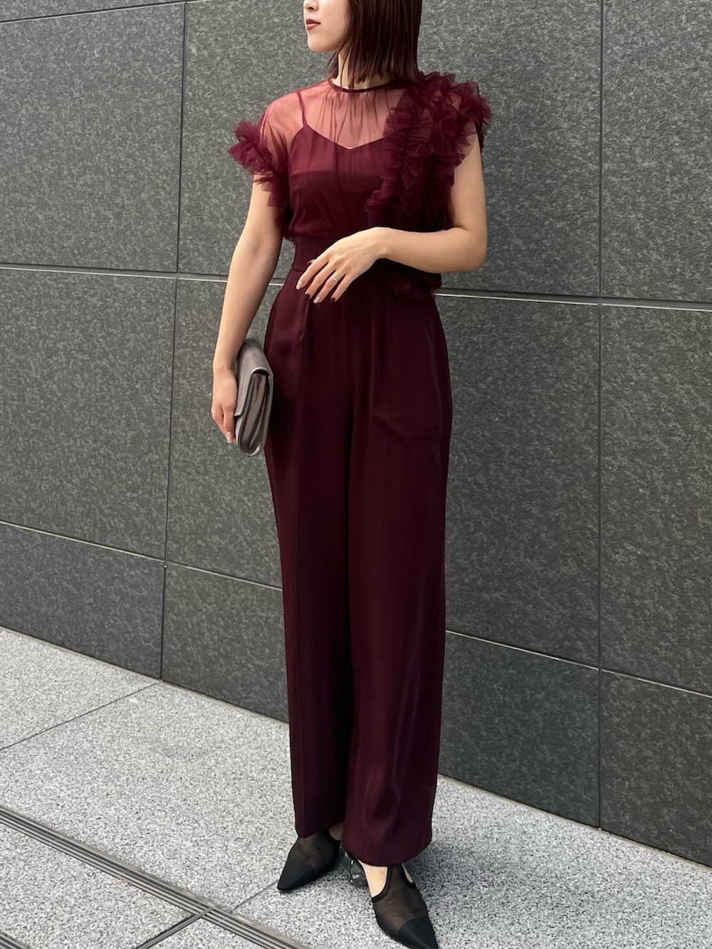 レッド系のパンツドレス、ホワイト系のチェスターコートを着用したレディースの冬コーディネートの6枚目の写真