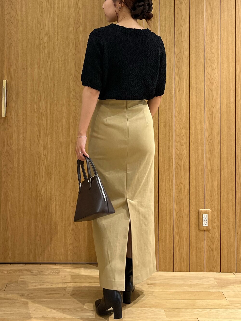 ブラック系のブーツ、ベージュ系のスカート、ブラウン系のボストンバッグを着用したレディースの秋コーディネートの3枚目の写真