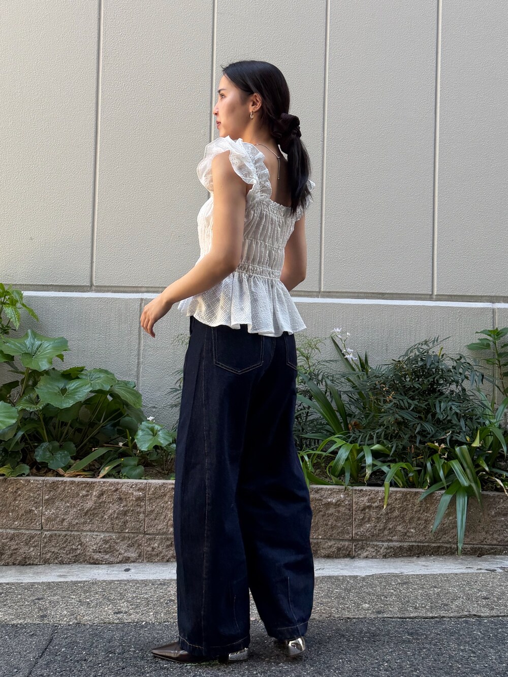 ブルー系のデニムパンツ、ブラウン系のハンドバッグ、ホワイト系のシャツ/ブラウスを着用したレディースの春コーディネートの2枚目の写真