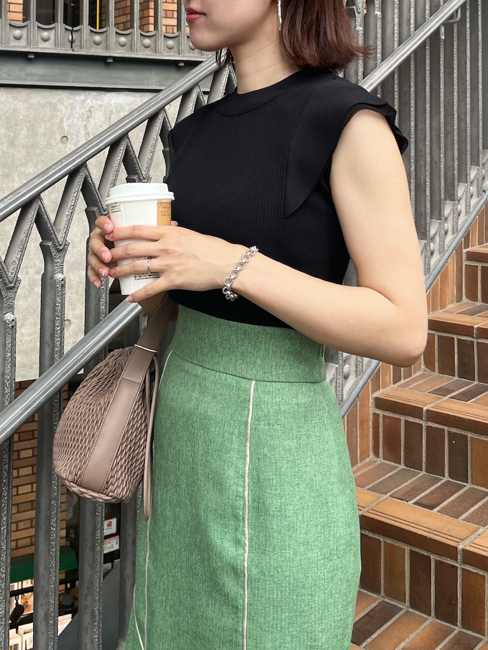 ブラック系のニット/セーター、グリーン系のスカート、ベージュ系のサンダルを着用したレディースの夏コーディネートの4枚目の写真