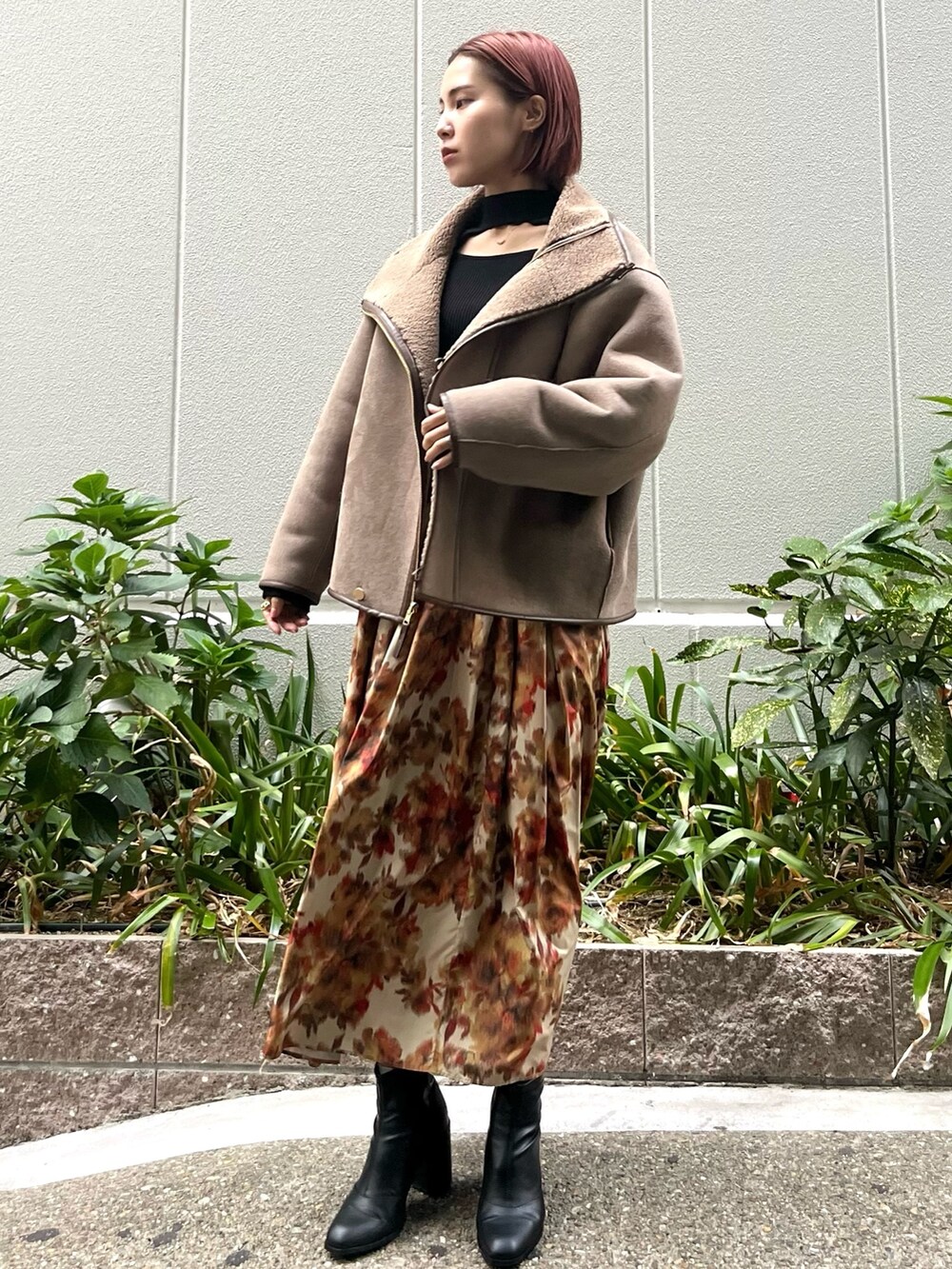 オレンジ系のスカート、ブラック系のニット/セーター、ベージュ系のムートンコートを着用したレディースの秋コーディネートの7枚目の写真