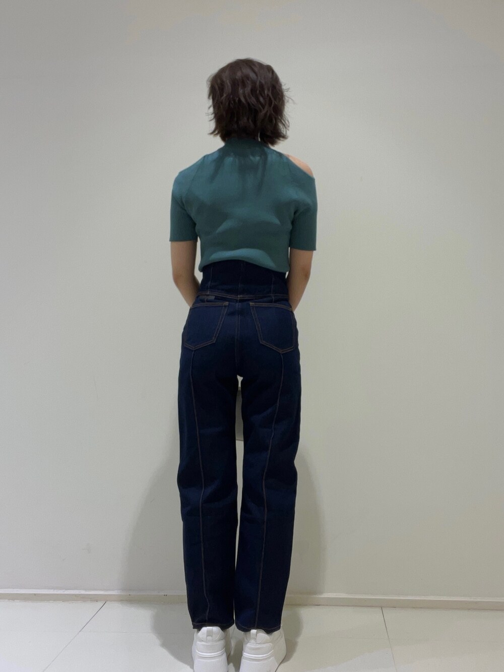 ブルー系のデニムパンツ、グリーン系のニット/セーター、ベージュ系のサンダルを着用したレディースの春コーディネートの4枚目の写真