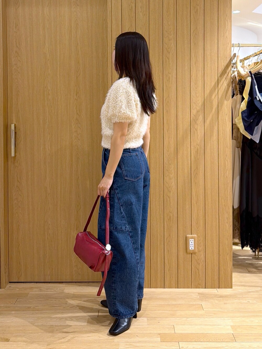 ブルー系のデニムパンツ、レッド系のハンドバッグ、ブラック系のブーツを着用したレディースの秋コーディネートの5枚目の写真