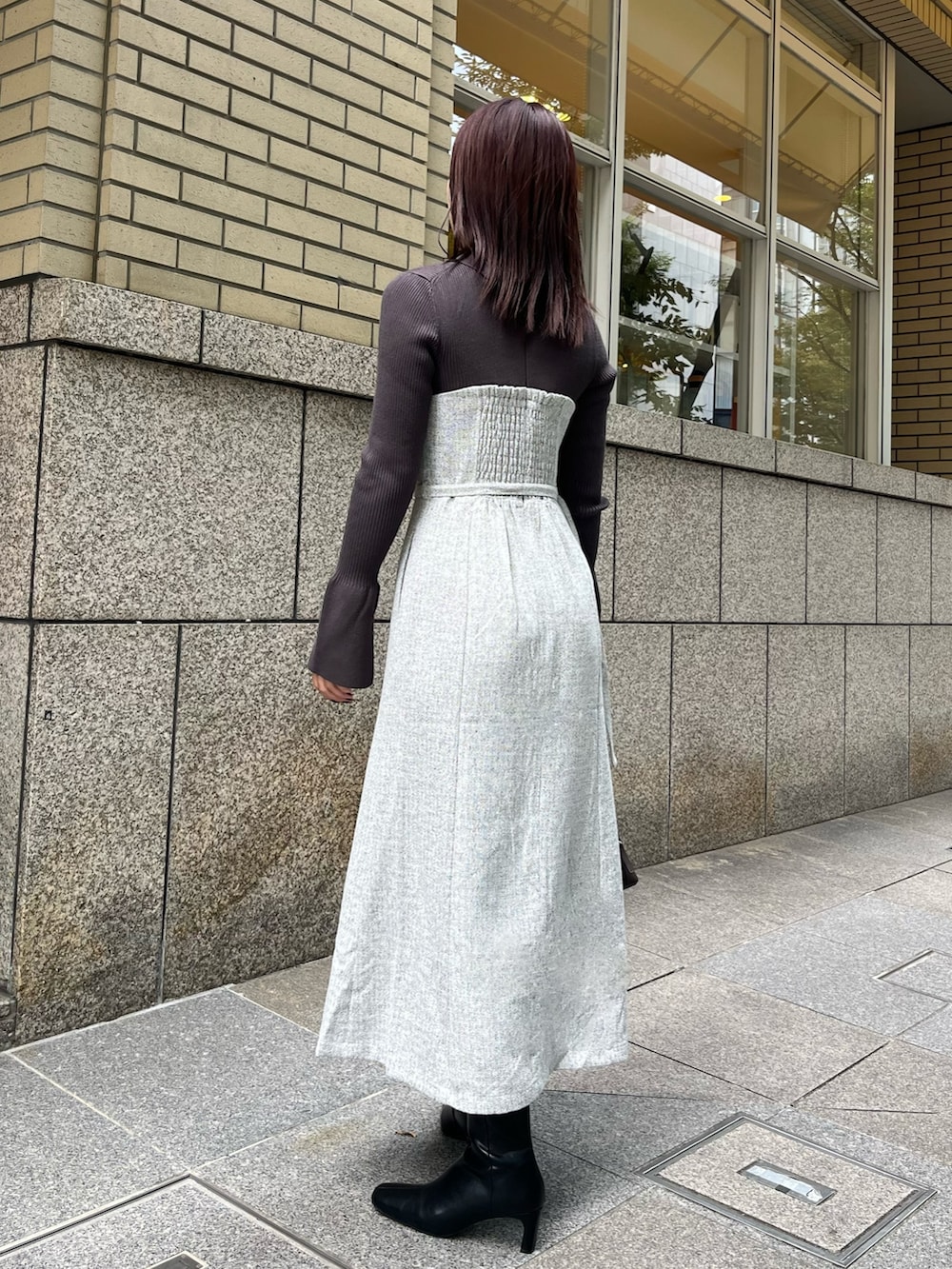 グレー系のワンピース、ブラウン系のボストンバッグ、ブラック系のブーツを着用したレディースの秋コーディネートの3枚目の写真