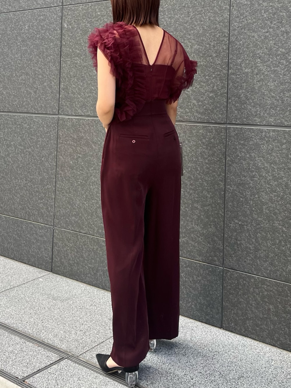 シルバー系のハンドバッグ、レッド系のパンツドレスを着用したレディースの冬コーディネートの3枚目の写真
