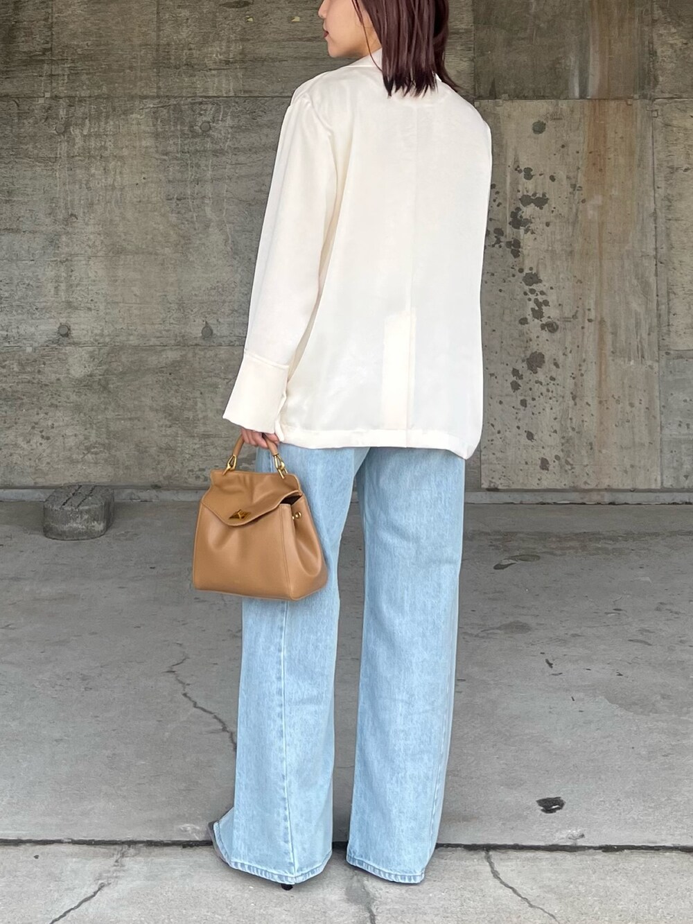 ブルー系のデニムパンツ、シルバー系のサンダル、ブラウン系のハンドバッグを着用したレディースの春コーディネートの3枚目の写真