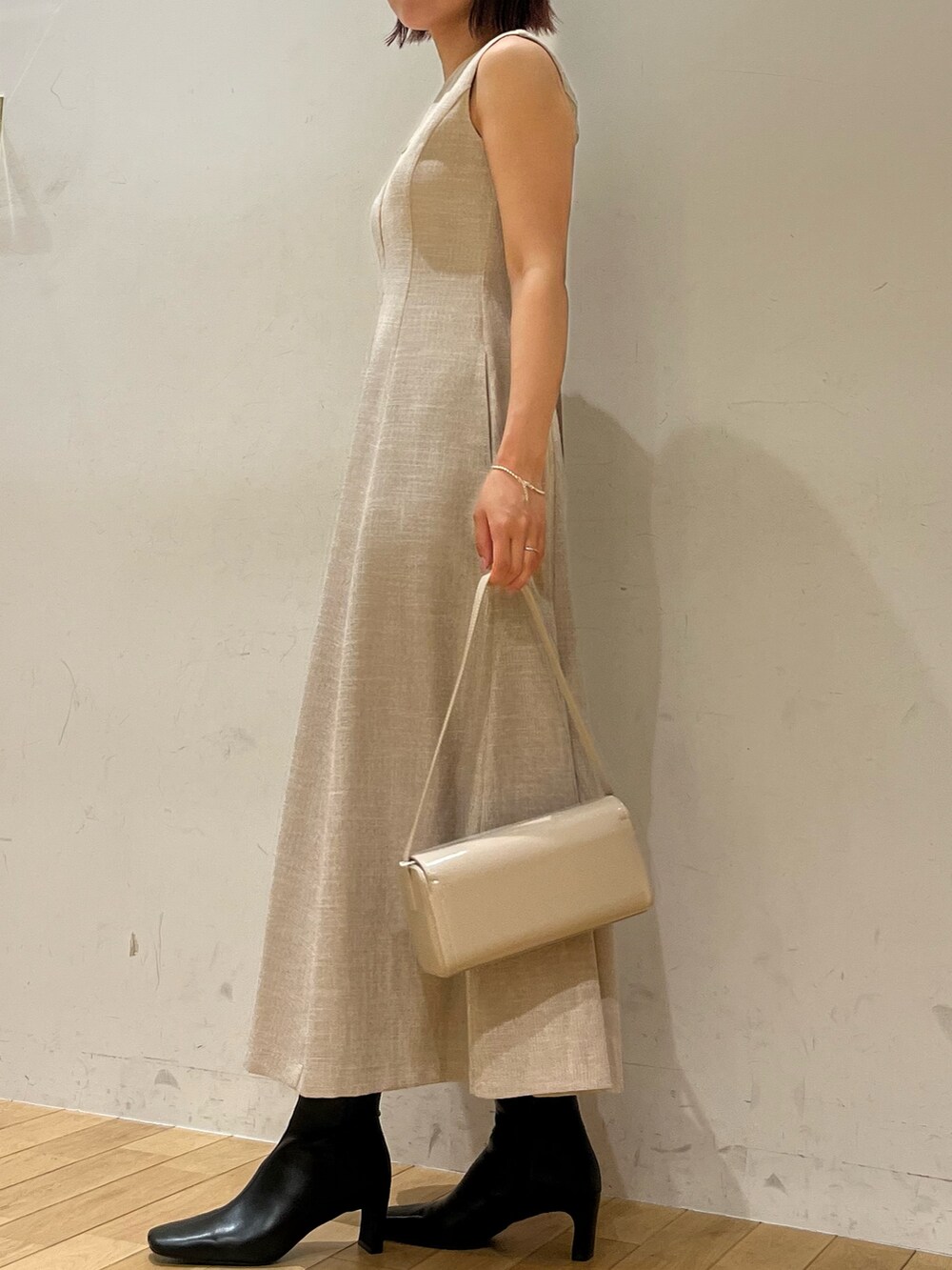 ホワイト系のショルダーバッグ、ベージュ系のワンピース、ブラック系のブーツを着用したレディースの夏コーディネートの2枚目の写真