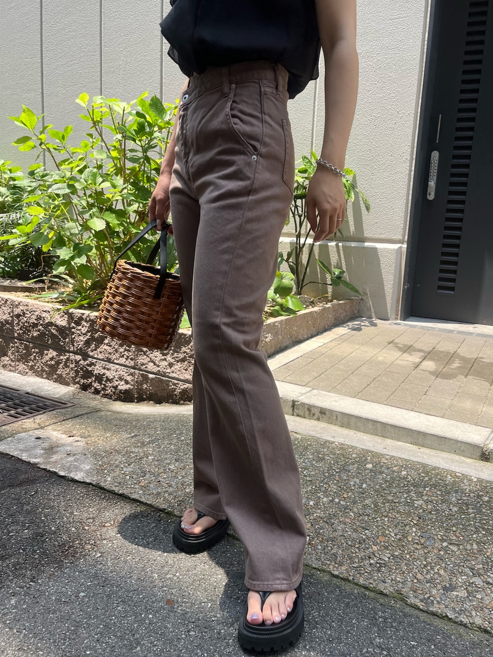 ベージュ系のデニムパンツ、ブラウン系のハンドバッグ、ブラック系のシャツ/ブラウスを着用したレディースの夏コーディネートの9枚目の写真