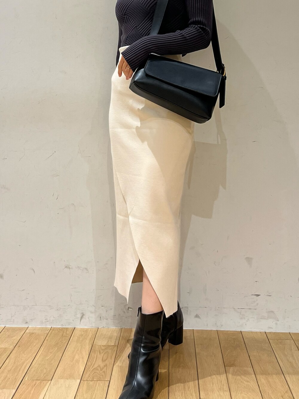 グレー系のニット/セーター、ブラック系のショルダーバッグ、ブラック系のブーツを着用したレディースの冬コーディネートの7枚目の写真