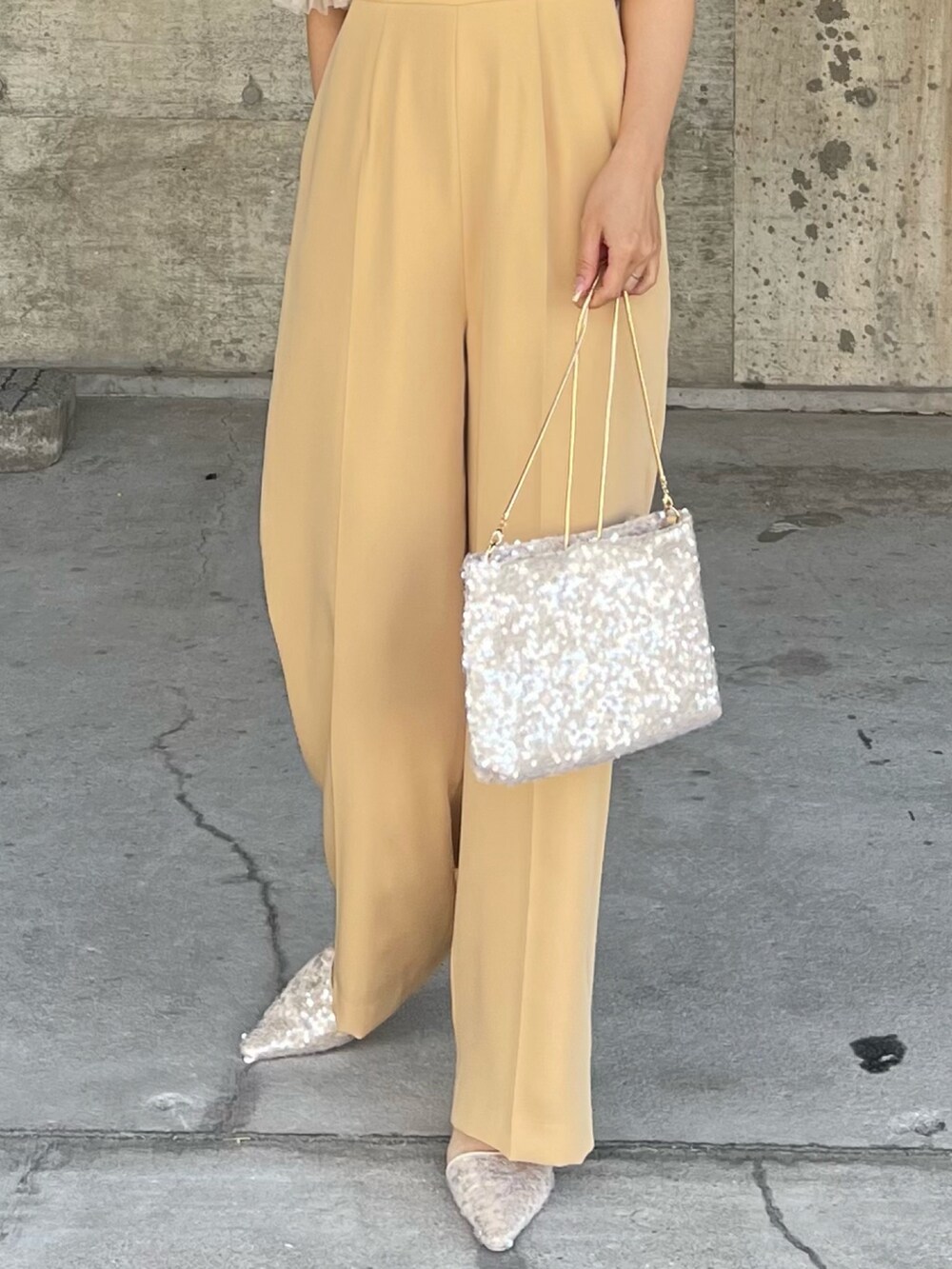 イエロー系のパンツドレス、ベージュ系のショルダーバッグ、ベージュ系のパンプスを着用したレディースの春コーディネートの7枚目の写真