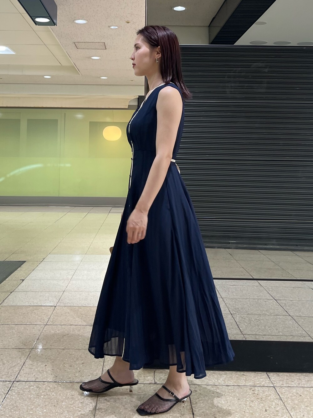 ブルー系のワンピース、ブラウン系のハンドバッグ、ブラック系のサンダルを着用したレディースの夏コーディネートの2枚目の写真