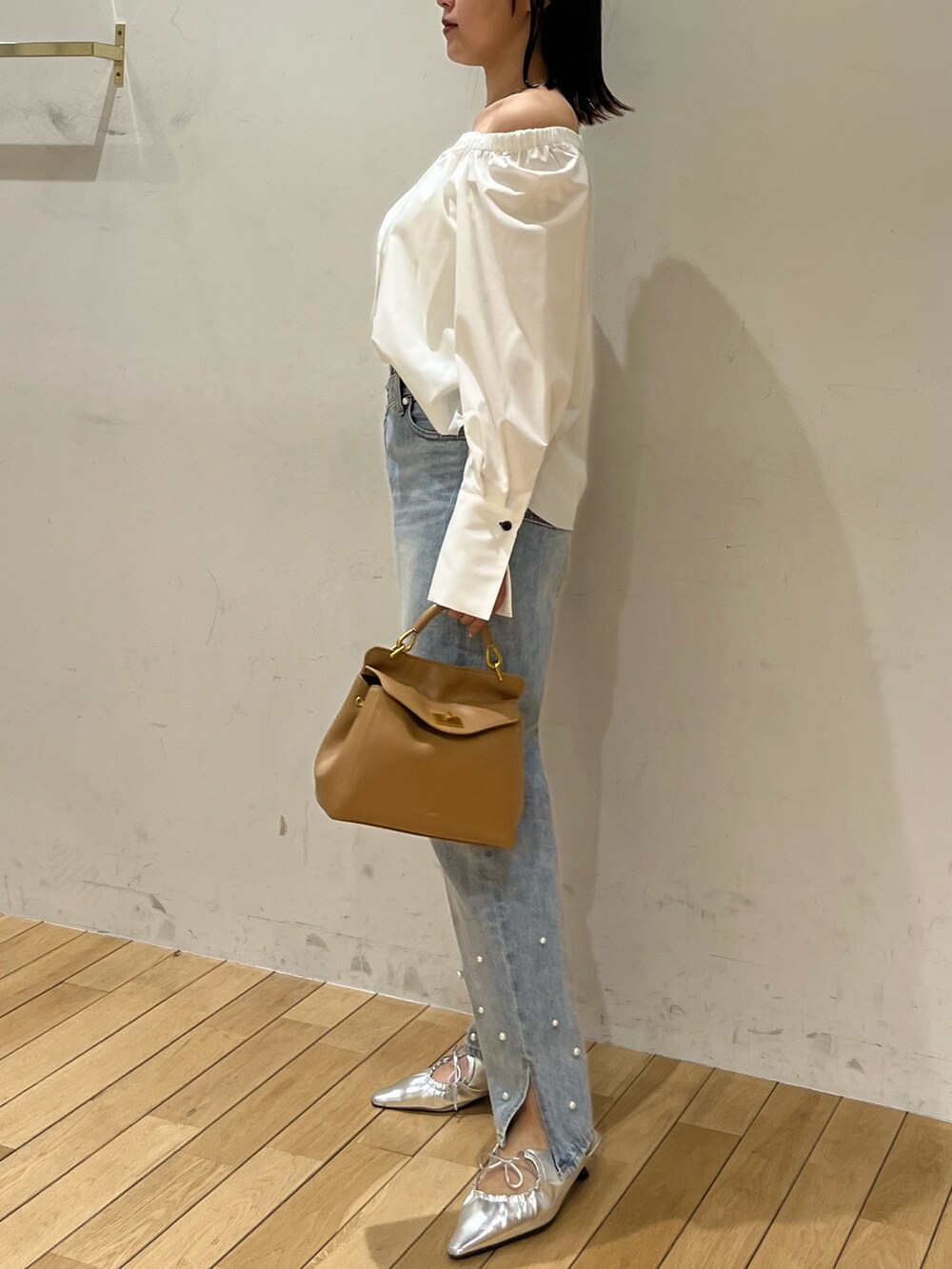 ブルー系のデニムパンツ、シルバー系のサンダル、ブラウン系のハンドバッグを着用したレディースの春コーディネートの2枚目の写真