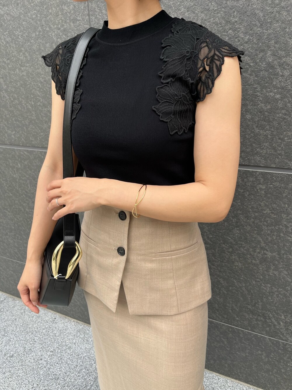 ブラック系のサンダル、ブラック系のニット/セーター、ベージュ系のスカートを着用したレディースの春コーディネートの6枚目の写真