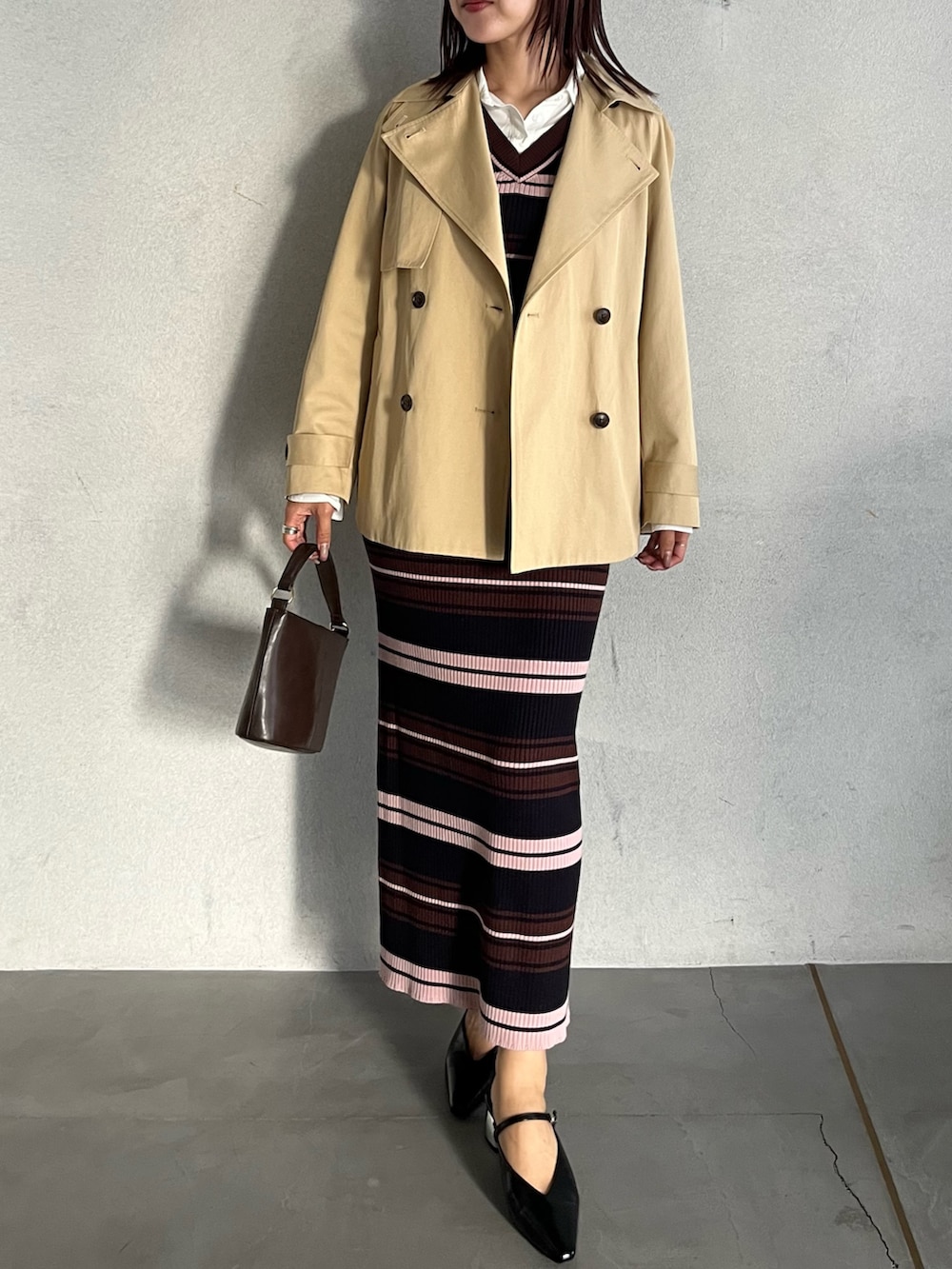 ブラウン系のハンドバッグ、ブラウン系のワンピース、ベージュ系のトレンチコートを着用したレディースの冬コーディネートの6枚目の写真