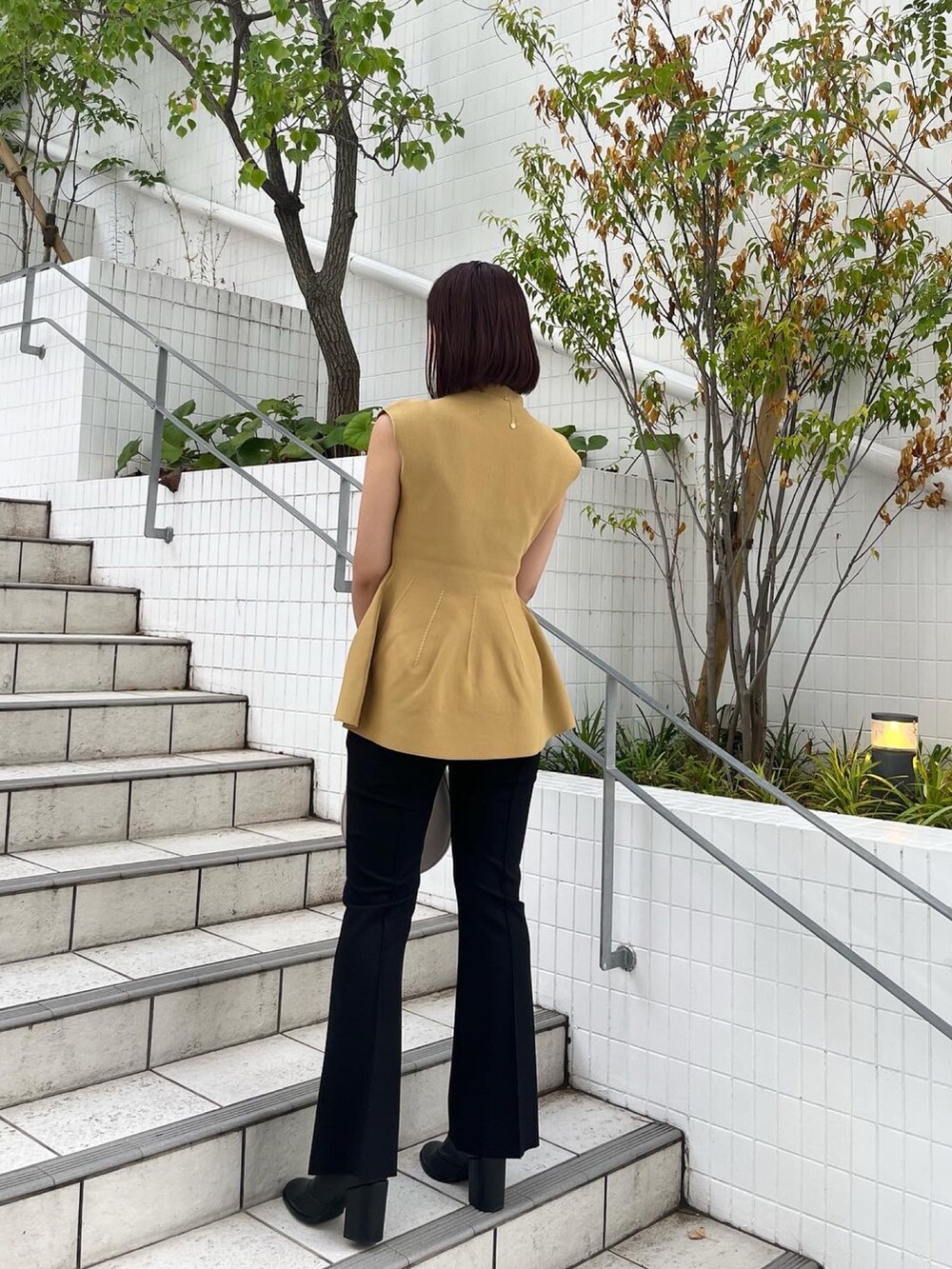 イエロー系のニット/セーター、ホワイト系のハンドバッグ、ブラック系のその他パンツを着用したレディースの秋コーディネートの3枚目の写真