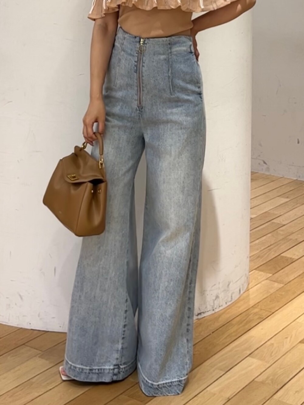 ブルー系のデニムパンツ、ホワイト系のサンダル、ブラウン系のハンドバッグを着用したレディースの春コーディネートの4枚目の写真