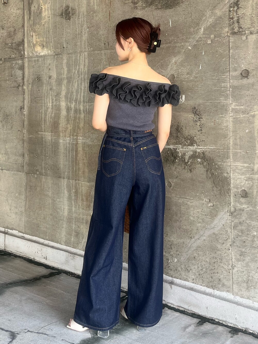 グレー系のニット/セーター、ブラウン系のハンドバッグ、ブルー系のデニムパンツを着用したレディースの夏コーディネートの3枚目の写真