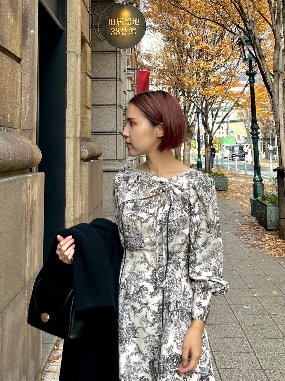 ホワイト系のワンピース、ブラック系のハンドバッグ、ブラック系のブーツを着用したレディースの冬コーディネートの4枚目の写真