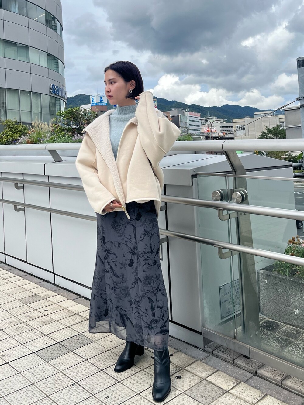 グリーン系のニット/セーター、ブラック系のハンドバッグ、グレー系のスカートを着用したレディースの秋コーディネートの6枚目の写真