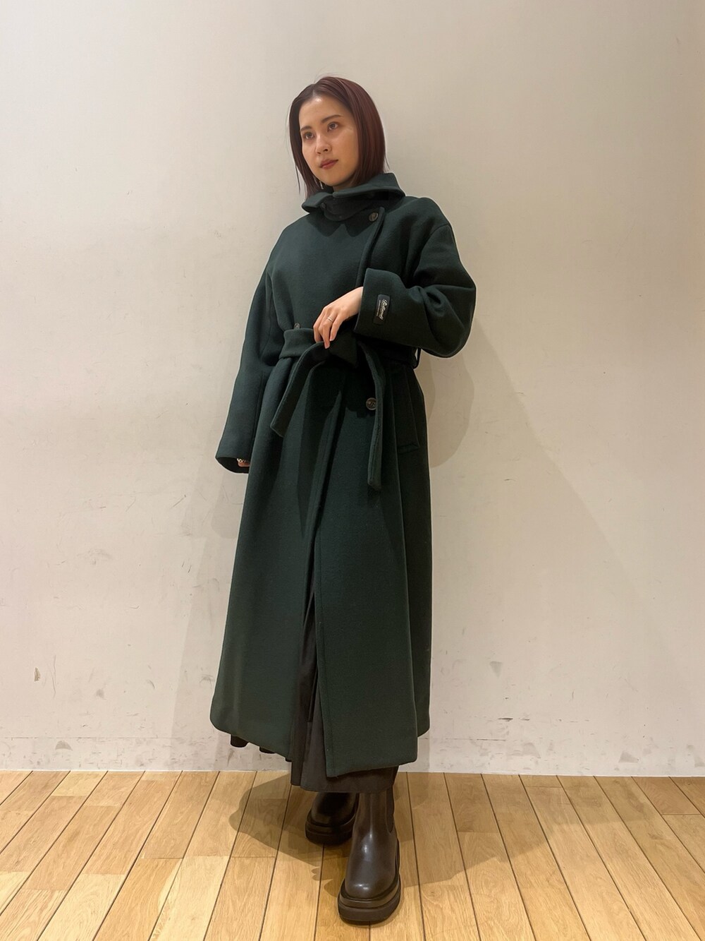 ブラック系のブーツ、グリーン系のニット/セーター、グリーン系のステンカラーコートを着用したレディースの冬コーディネートの2枚目の写真