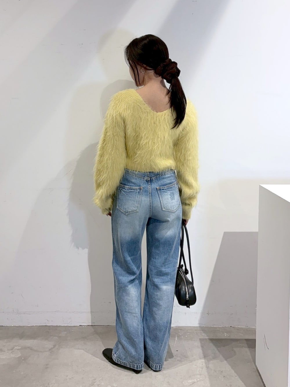 ブルー系のデニムパンツ、ブラック系のブーツ、イエロー系のニット/セーターを着用したレディースの秋コーディネートの3枚目の写真