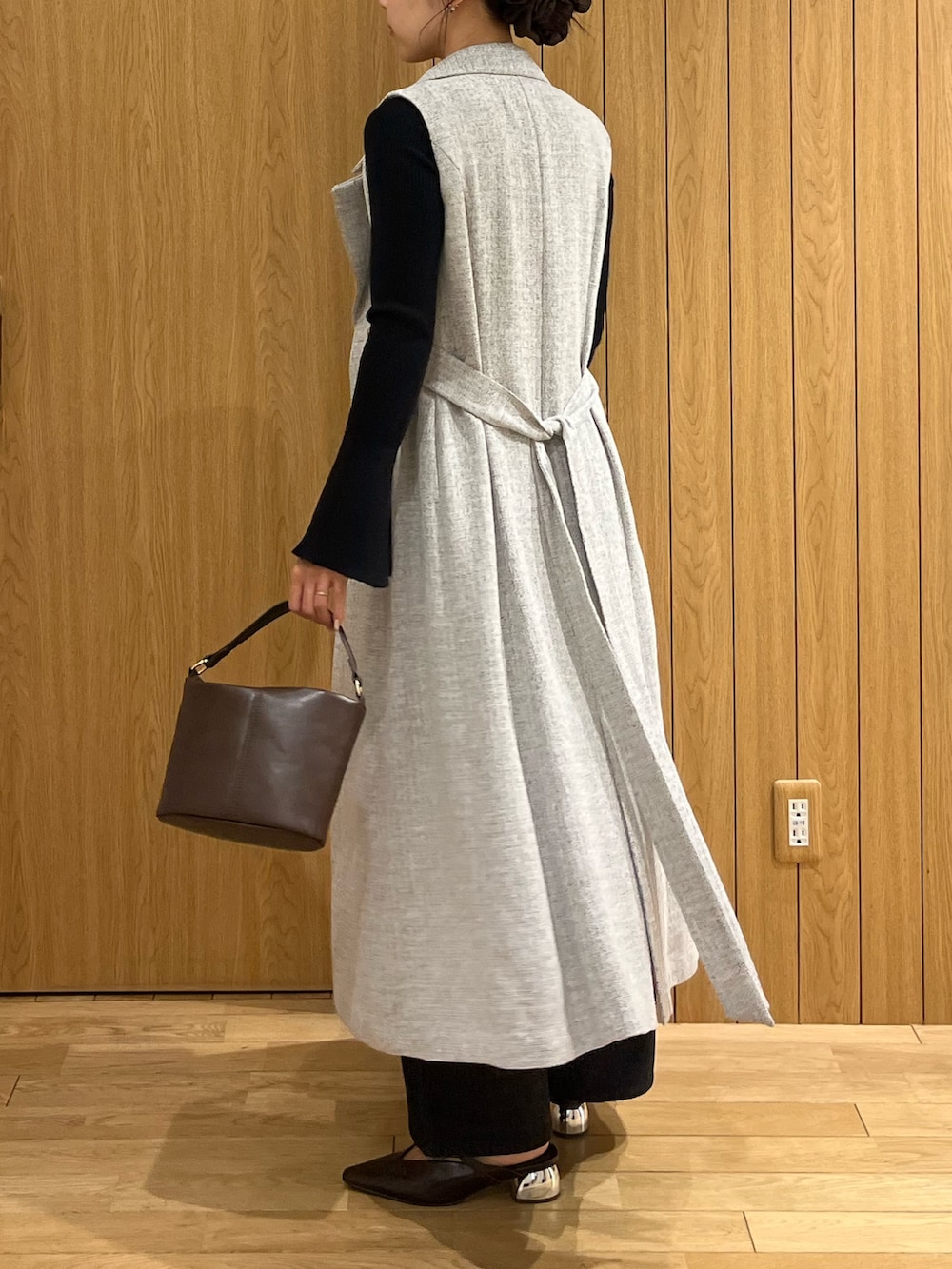 ブラウン系のハンドバッグ、ブラック系のデニムパンツ、グレー系のワンピースを着用したレディースの秋コーディネートの3枚目の写真