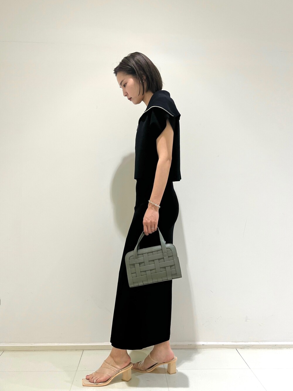 ブラック系のスカート、ブラック系のニット/セーター、グリーン系のショルダーバッグを着用したレディースの春コーディネートの3枚目の写真