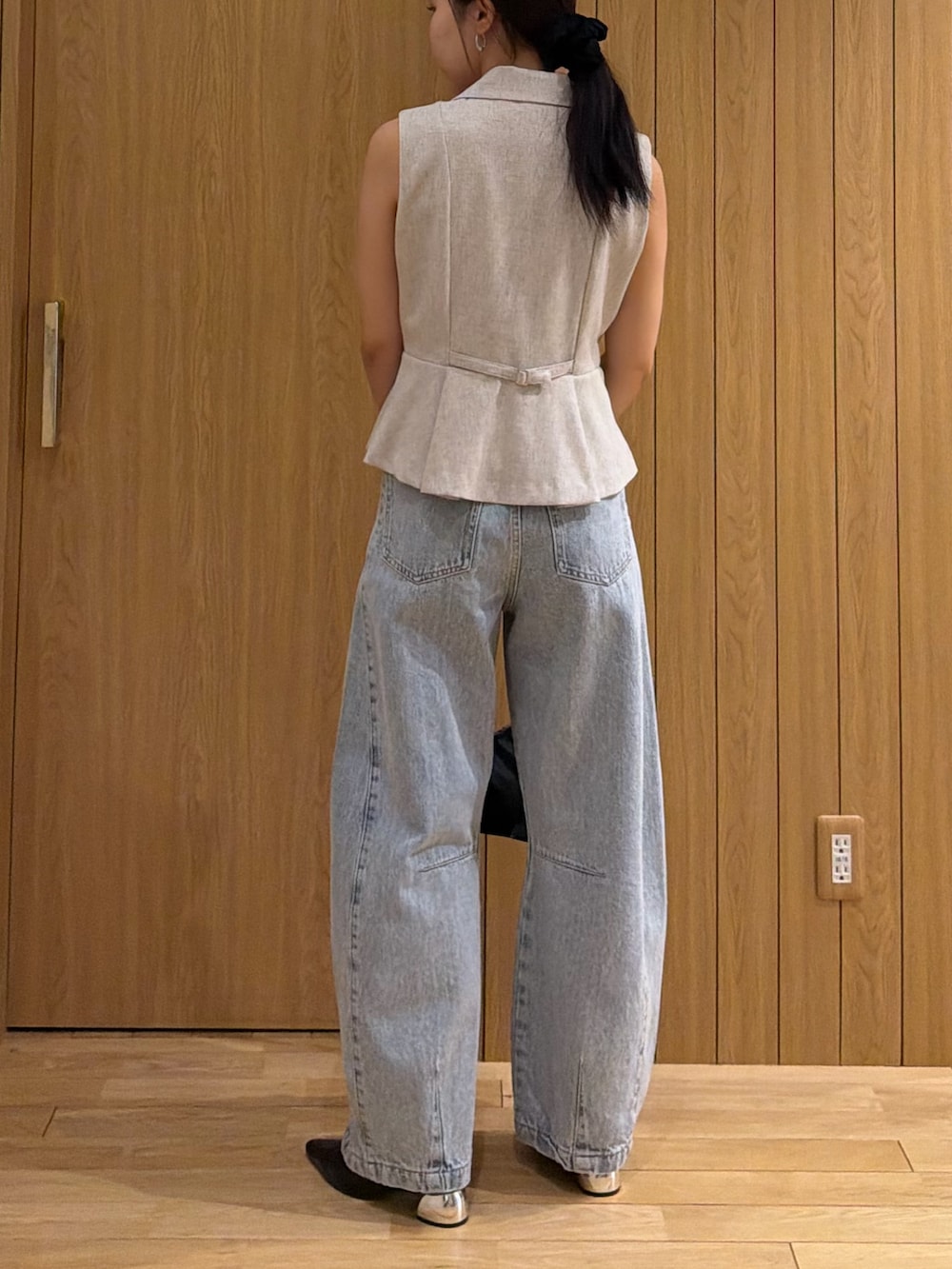 ブルー系のデニムパンツ、ホワイト系のベストを着用したレディースの春コーディネートの3枚目の写真